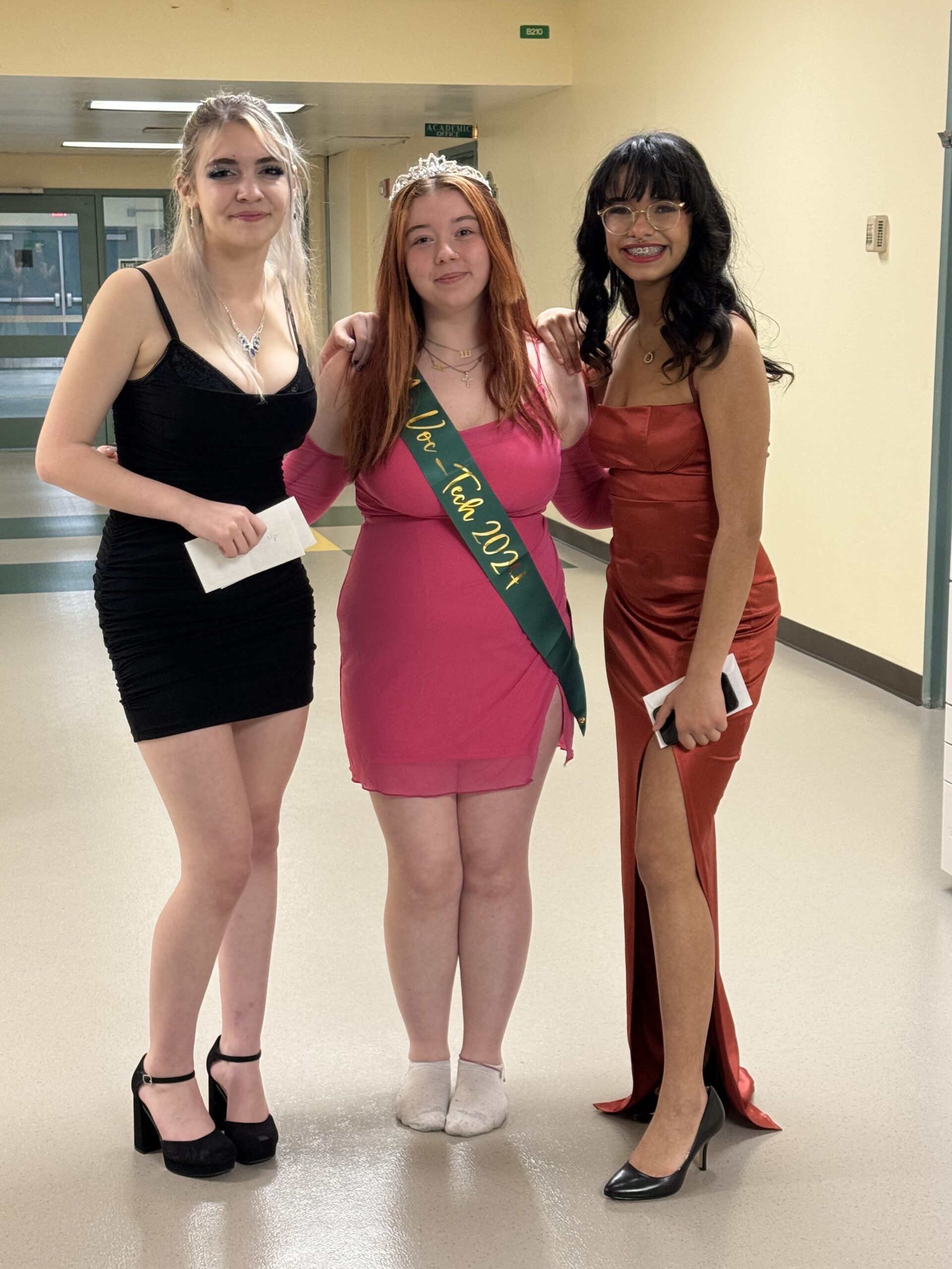 three students posing for a photo wearing fancy dresses