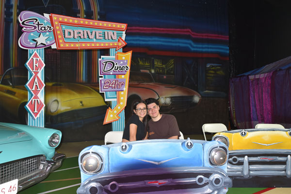 a couple taking a photo with the drive in diner backdrop at the 2024 afterprom