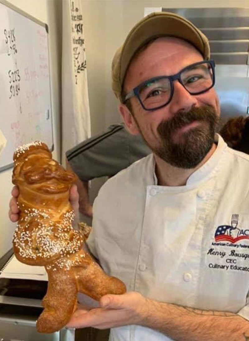 alumni spotlight chef henry showing off bread that looks like a man
