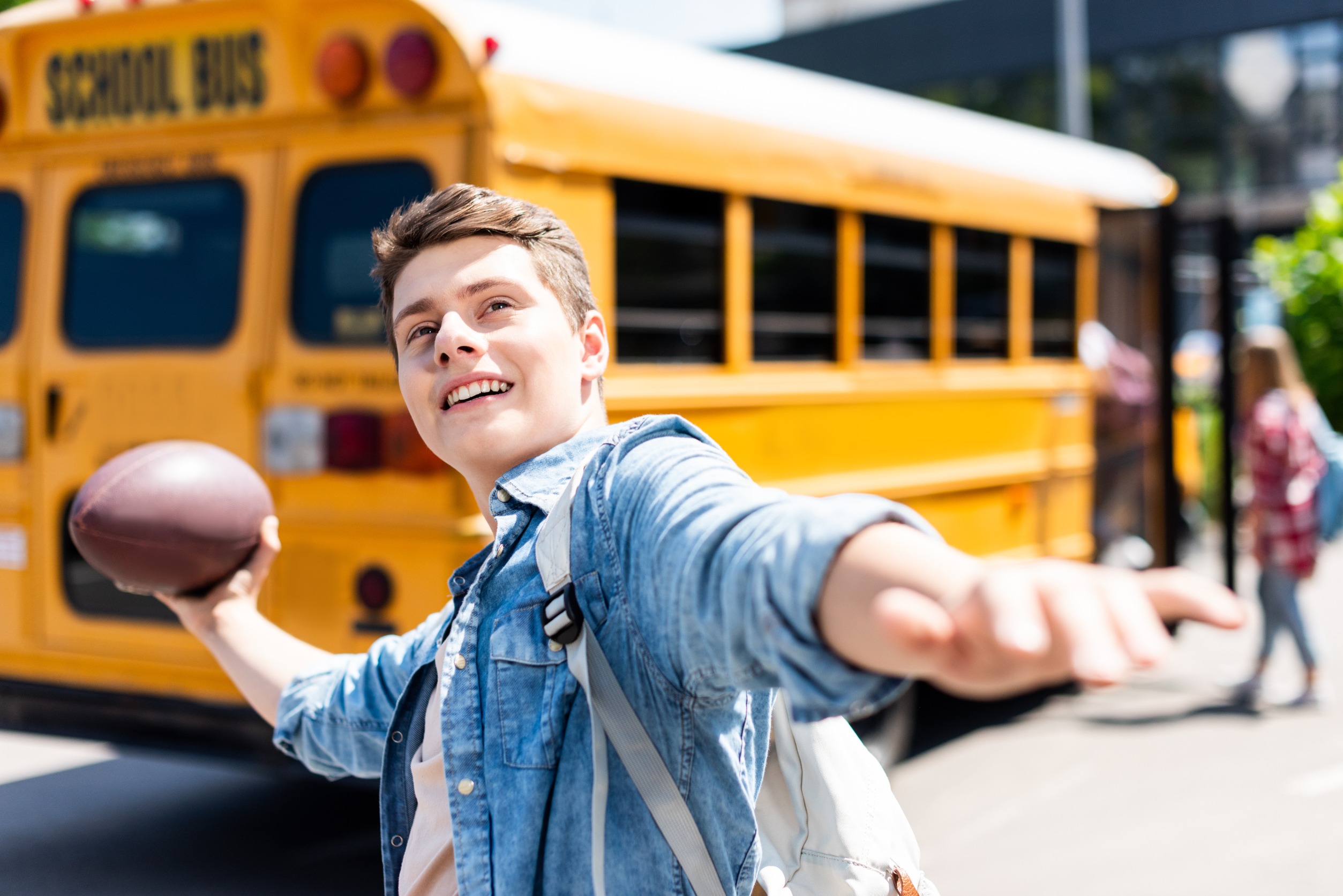 Male student aiming football in front of school