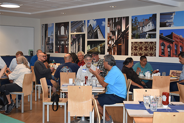 A room full of adults eating breakfast at tables.