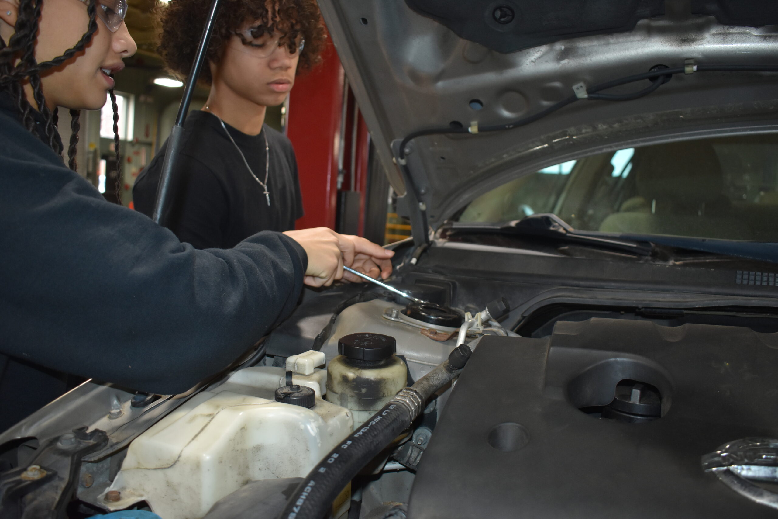 Two students working together on a car putting in screws.