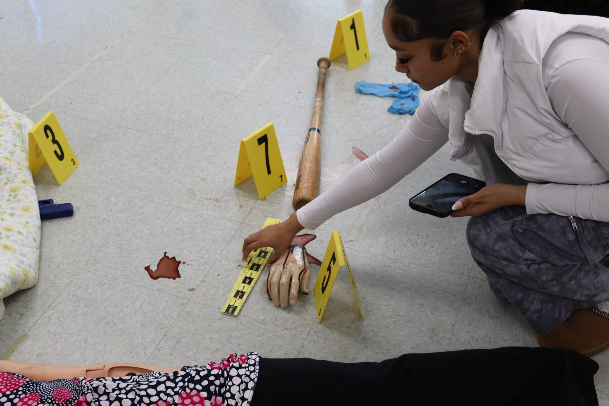 A student placing down a ruler to measure the size of a piece of evidence.