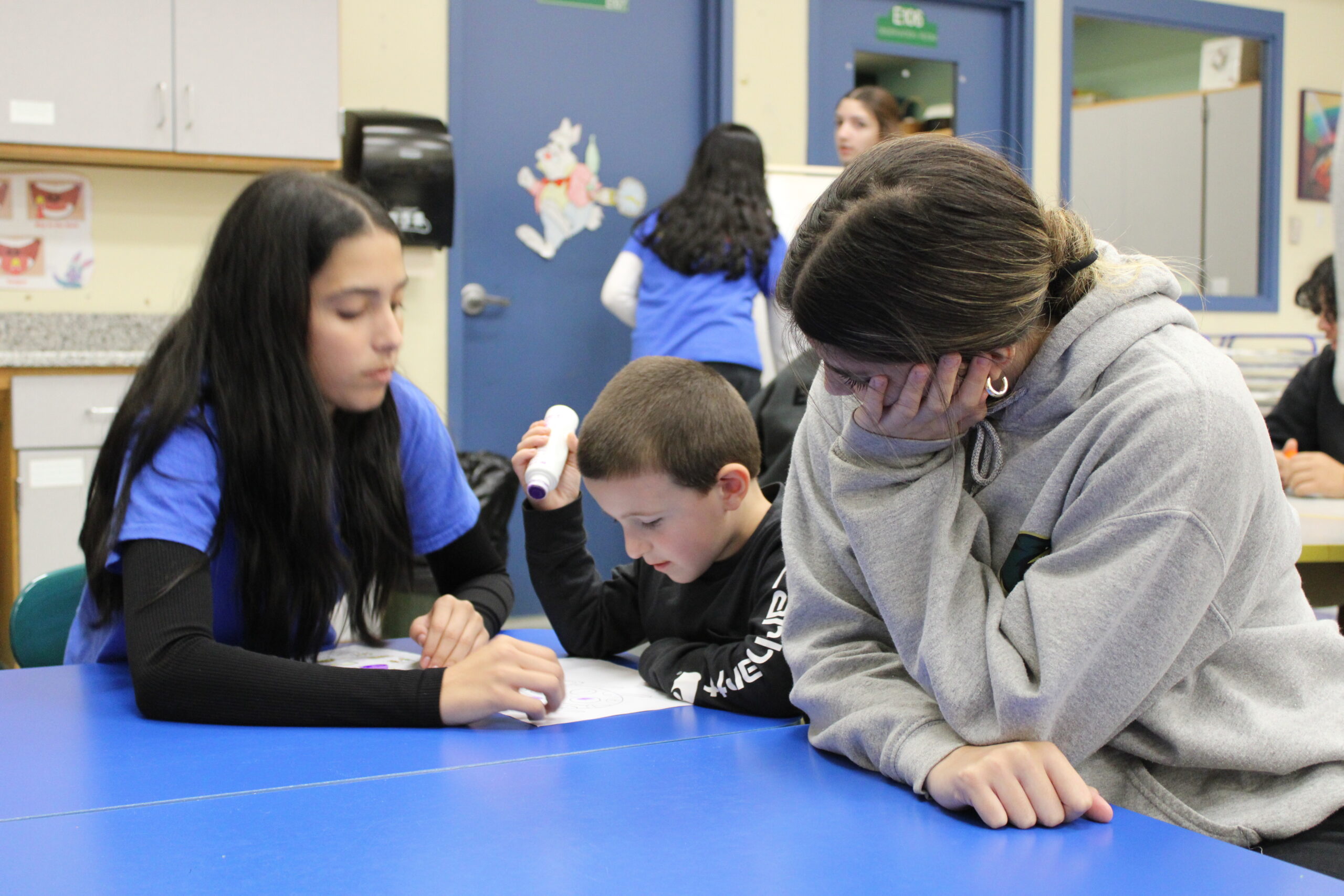 Early Childhood students helping a child with their project<br />
