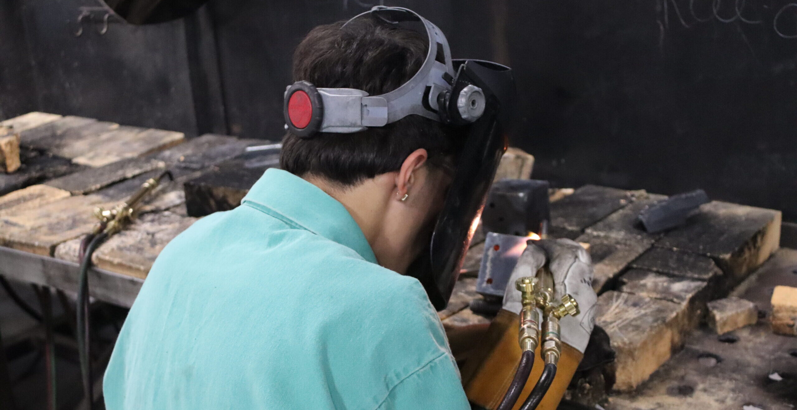 Metal Fabrication student using torch to weld a project together