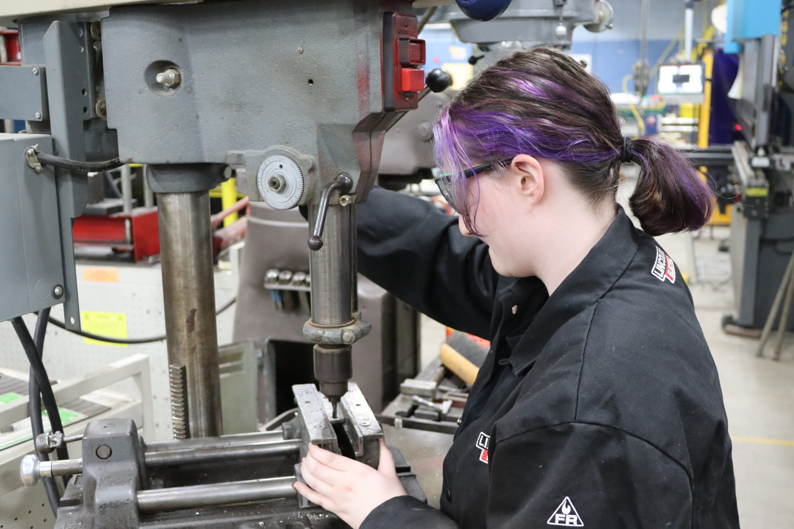 Metal Fabrication student using machine to drill holes into metal sheets