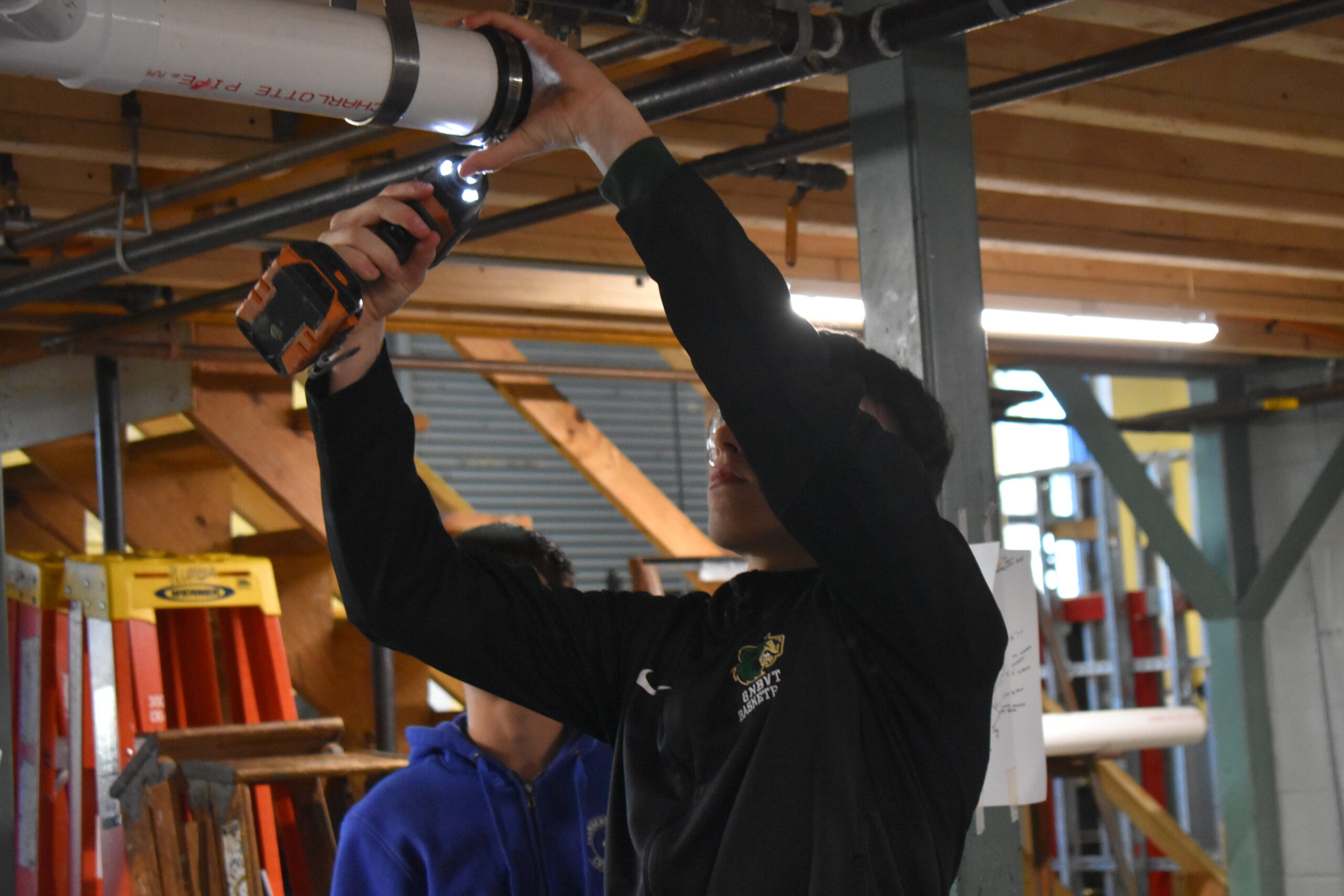 Student using a impact driver to install the pipe clamp