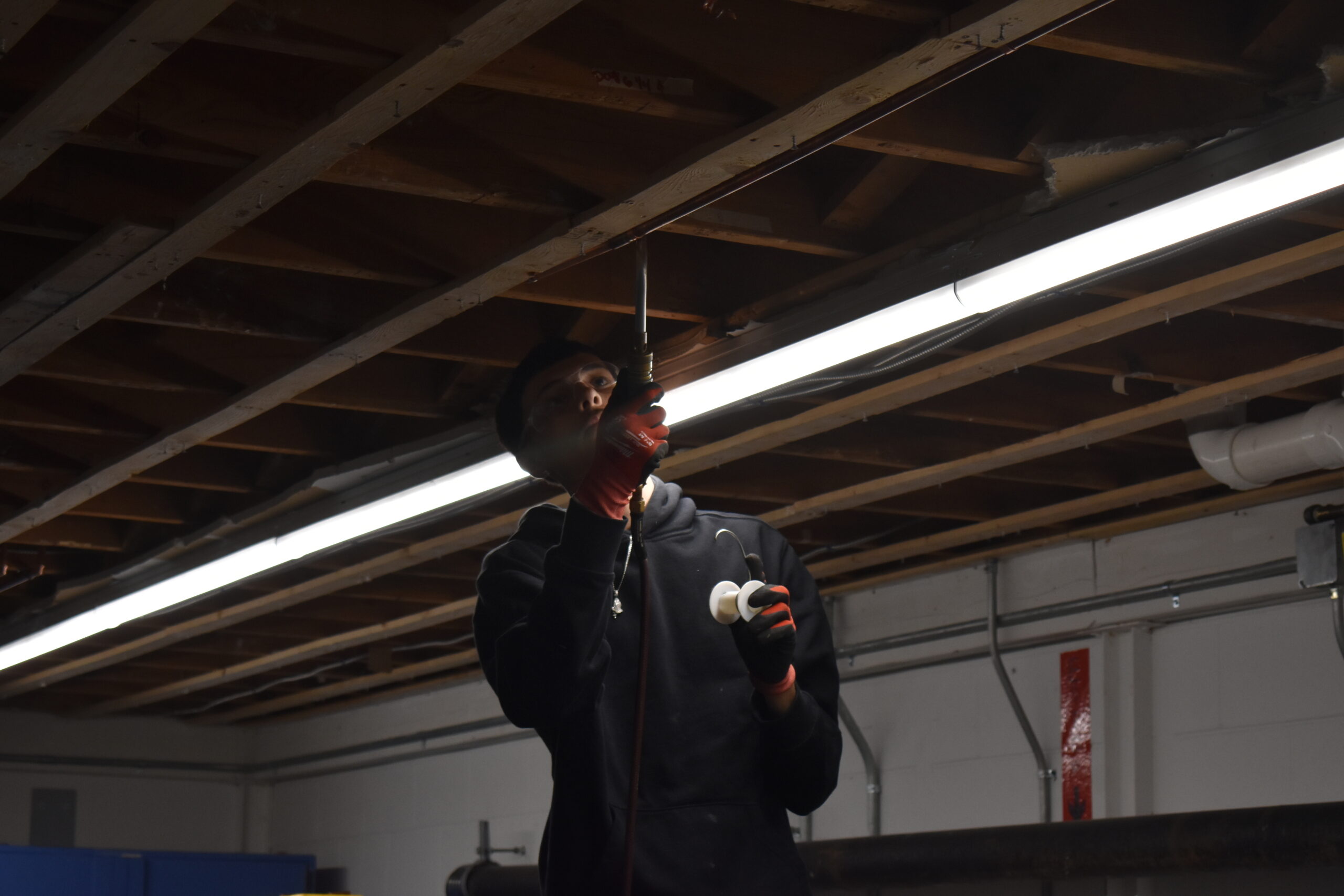  Student soldering a fitting in the ceiling