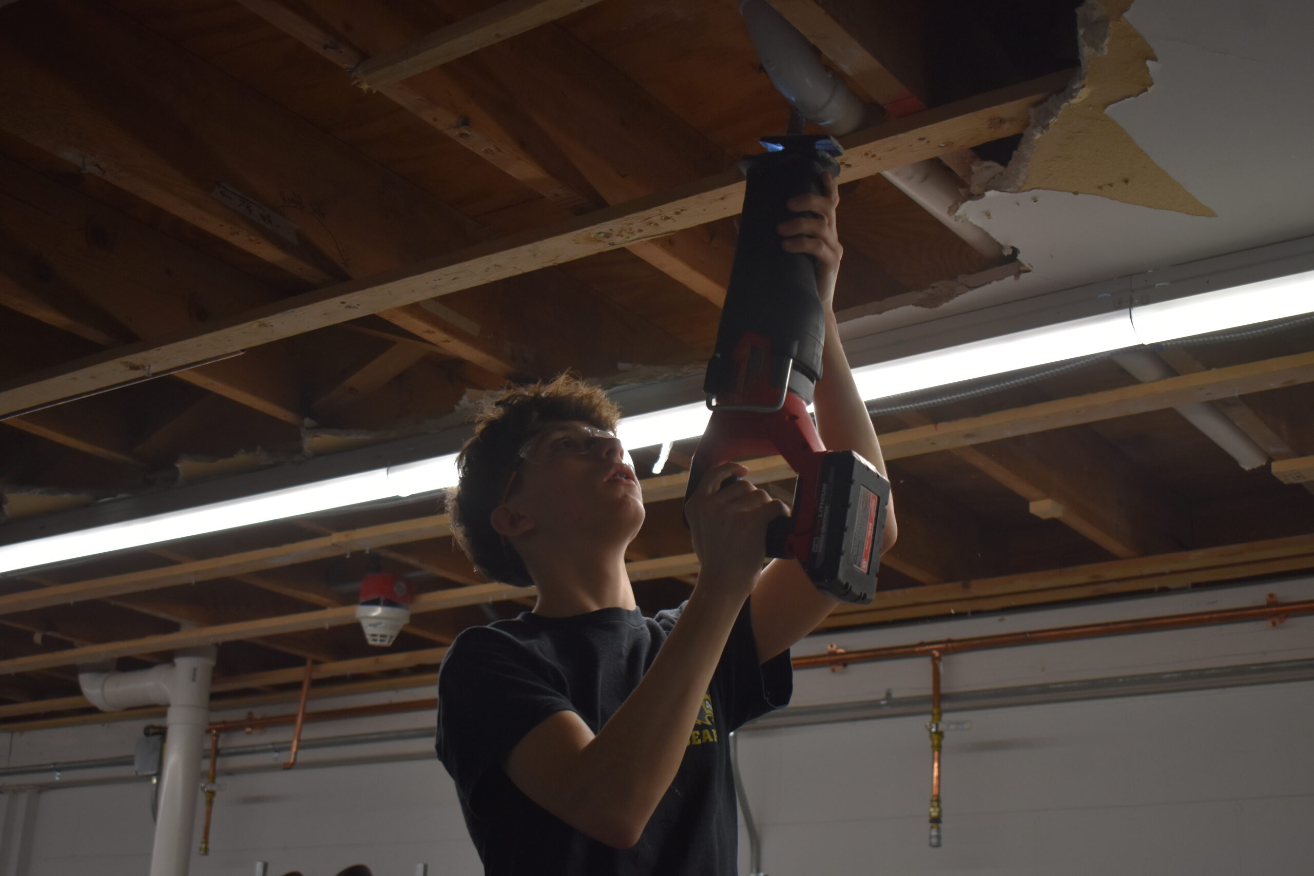  Student using a sawzall to fix a drain pipe